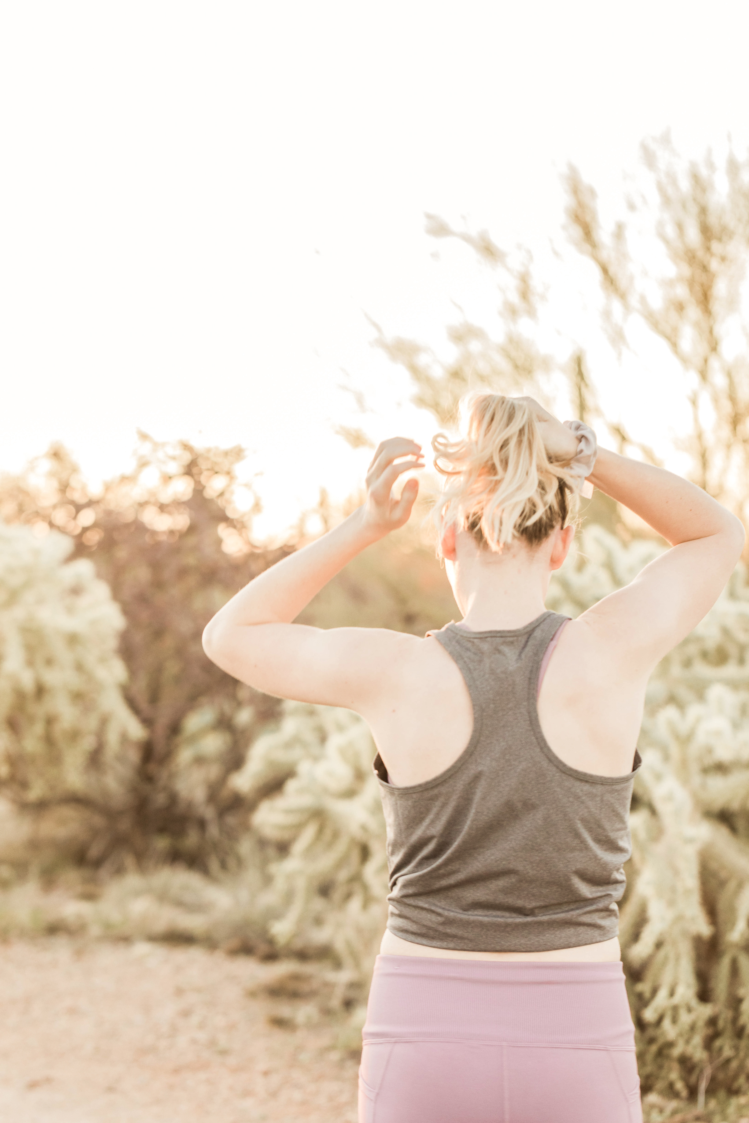 woman in exercise gear fixing ponytail before working out